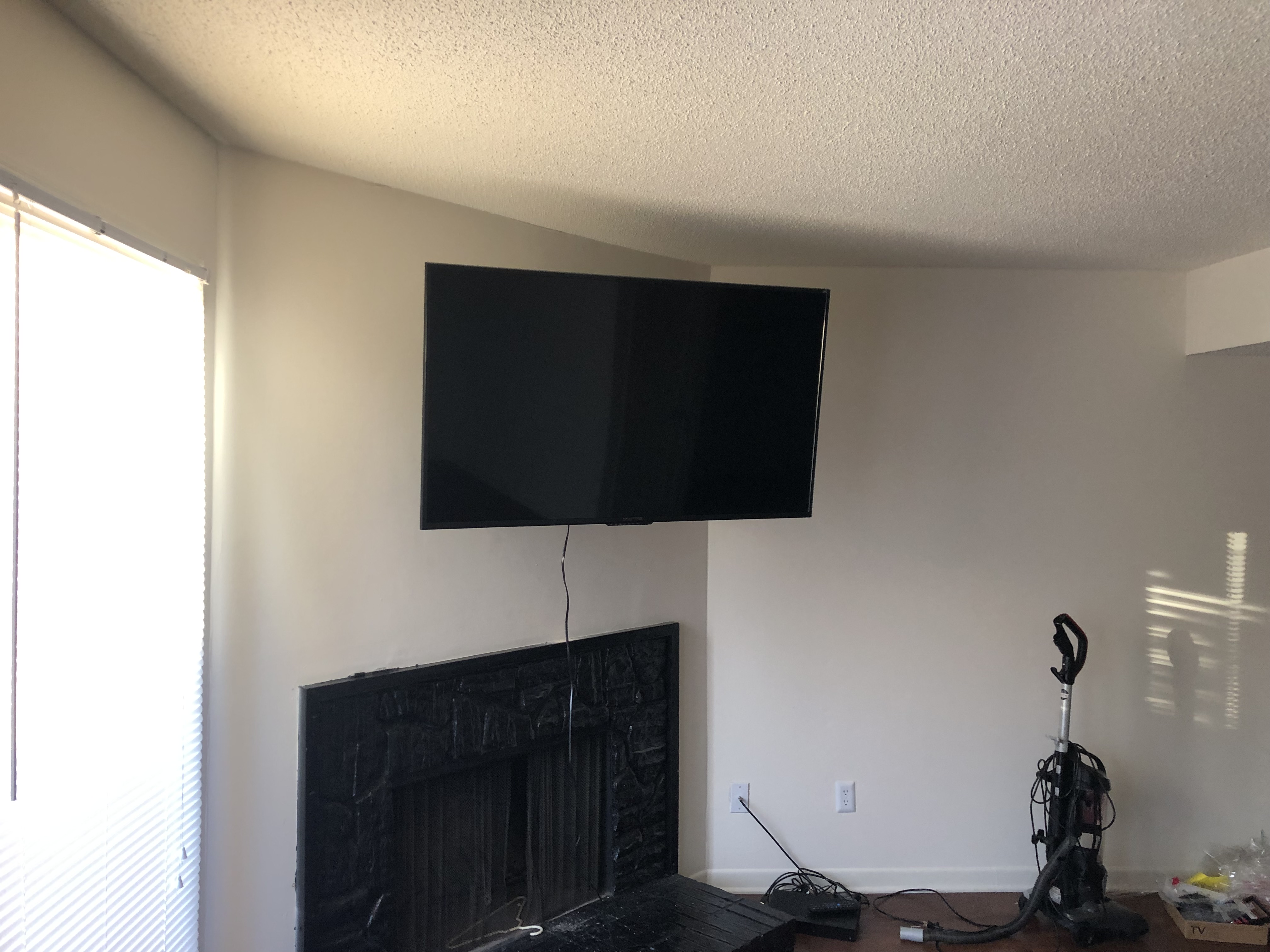 Full-motion TV mounting on drywall wall in living room, service area
